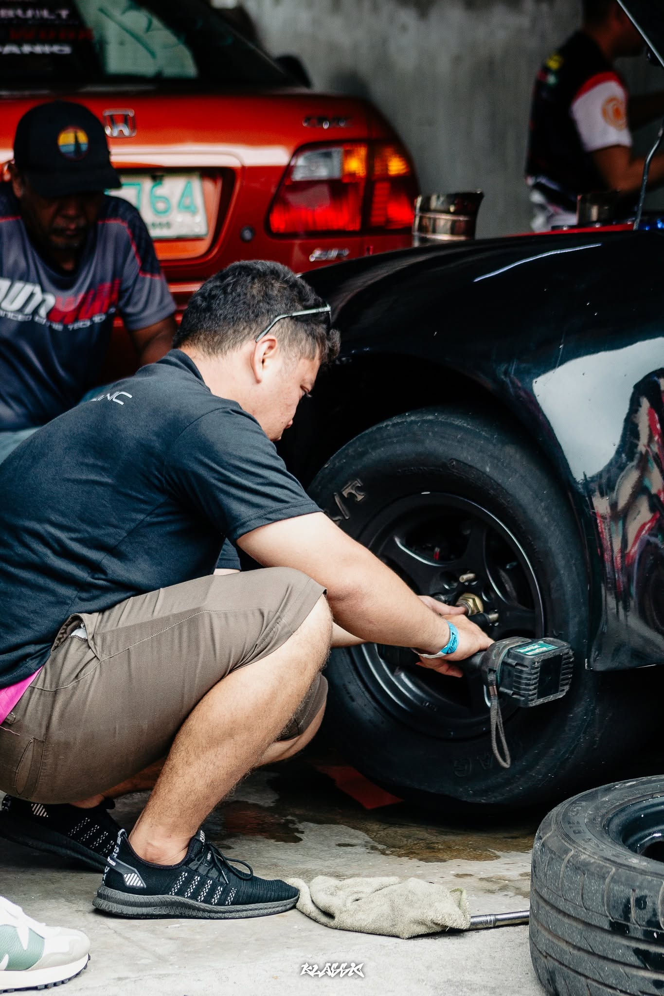 A GridUno community member working on a car's wheel in a garage
