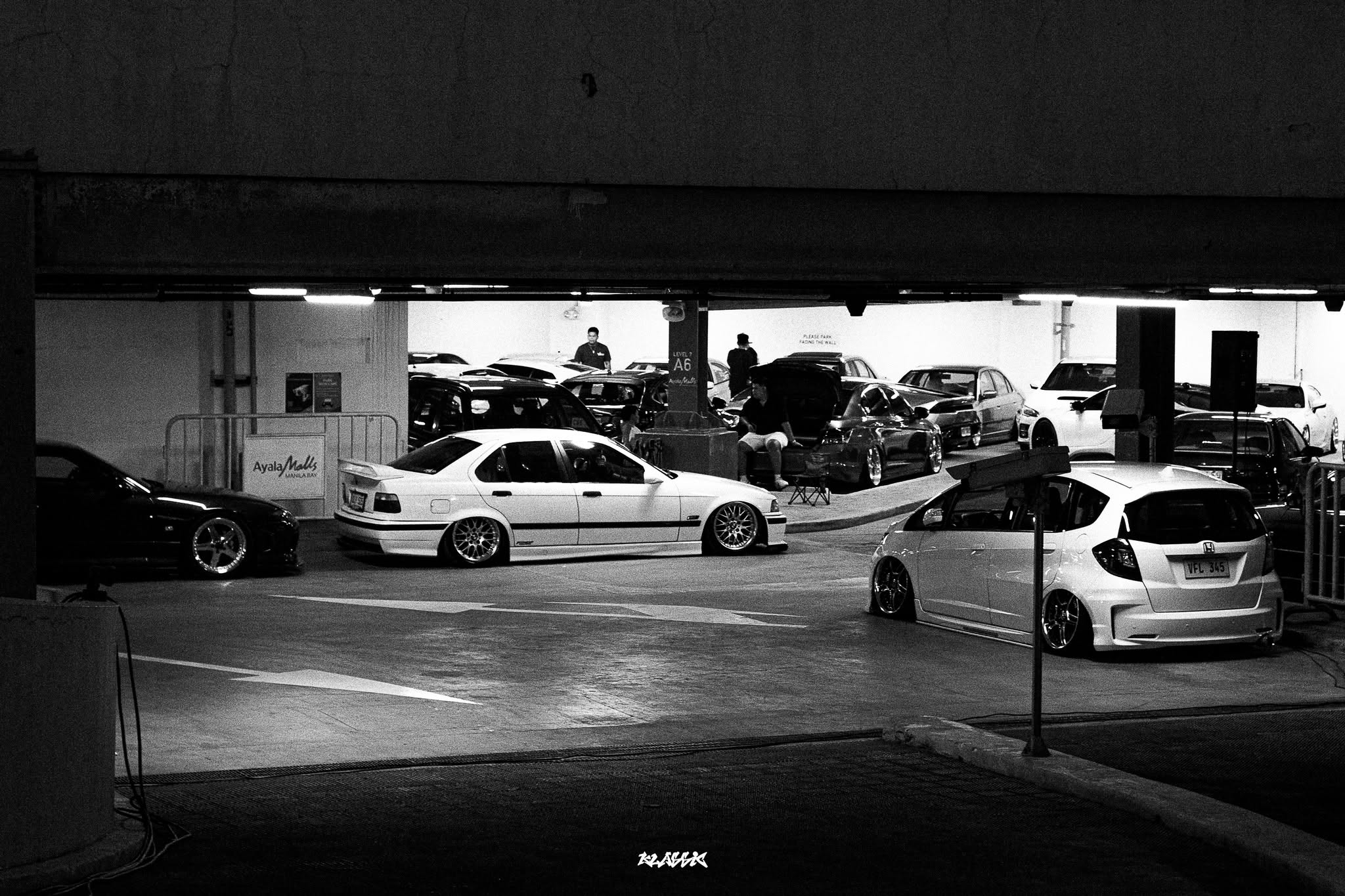 Modified cars gathered in a parking structure at a nighttime car meet